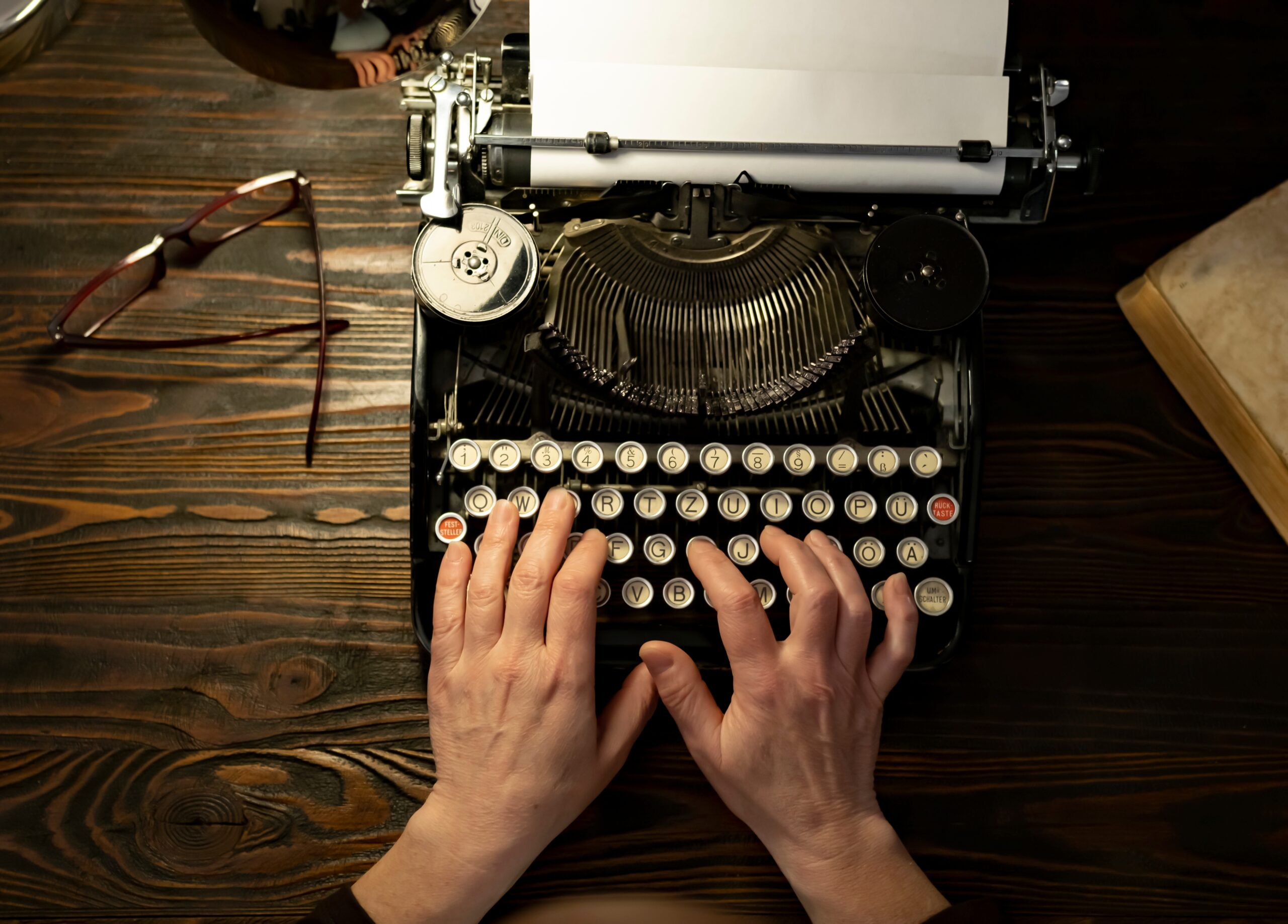 Hands typing on a vintage typewriter.