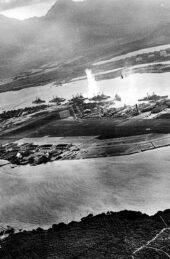 Black and white photograph of Pearl Harbor during the torpedo attack, from an aerial view from the Japanese planes.