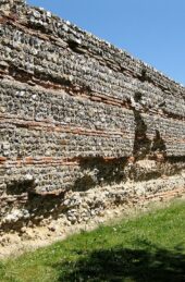 Photograph taken in 2011 of the Gariannonum Burgh Castle south wall, well preserved, against a blue sky.